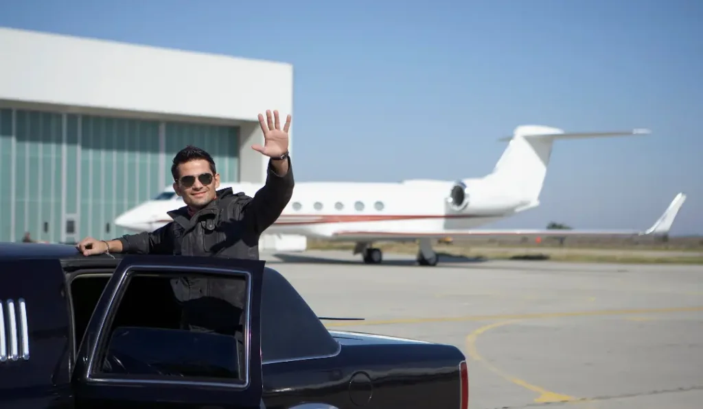 man waving from limo at airport